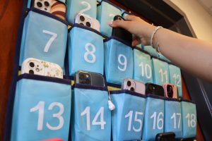 Student putting their cellphone into a phone caddy. These caddies are now present in every classroom on campus. 