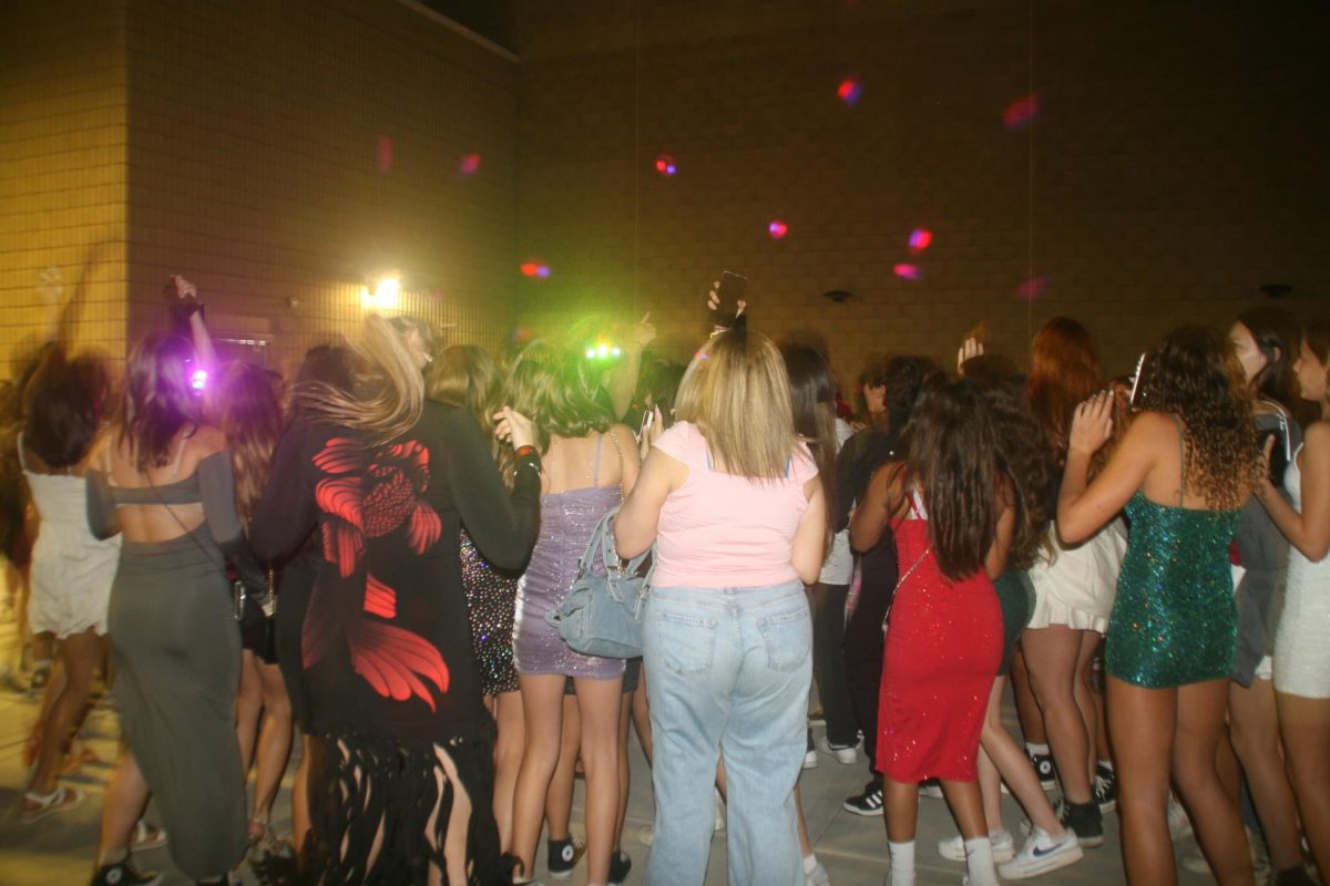 Students dance inside the amphitheater. The room was adorned with vibrant lights as students gathered around the live DJ.