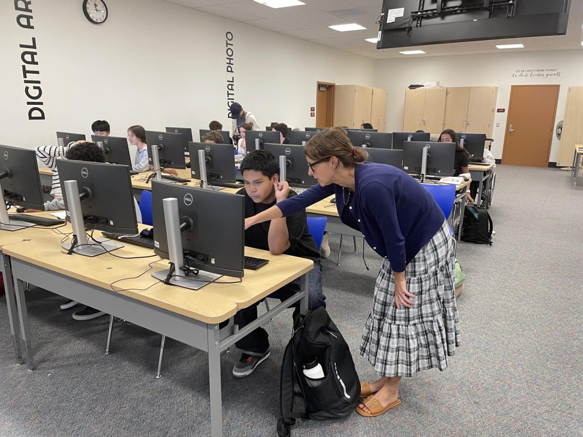 During class, Casassa assists a student on the computer.