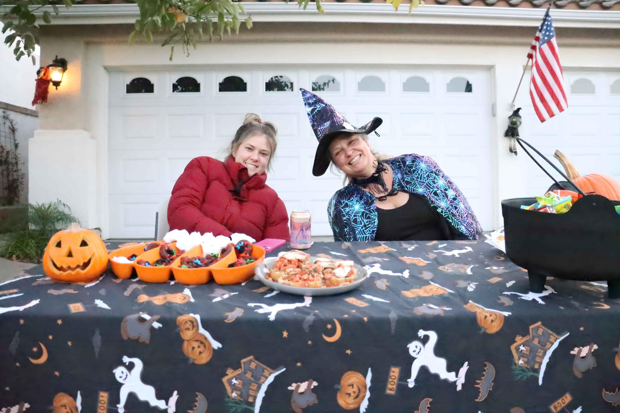 Trick-or-treaters stand in awe before a married skeleton couple and small ghosts. This house was one of many on the street that take pride in their vibrant Halloween decorations.