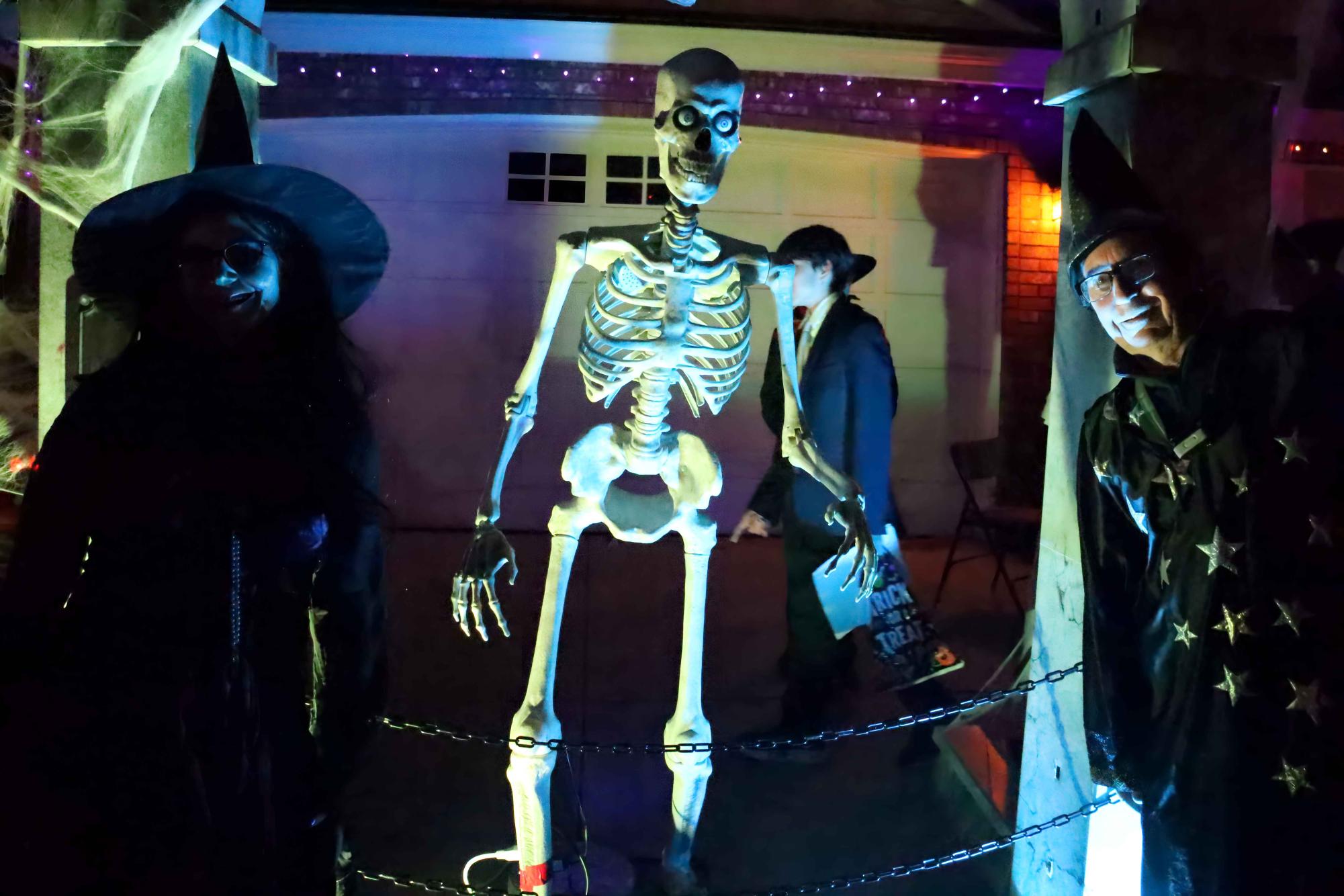 Trick-or-treaters stand in awe before a married skeleton couple and small ghosts. This house was one of many on the street that take pride in their vibrant Halloween decorations.