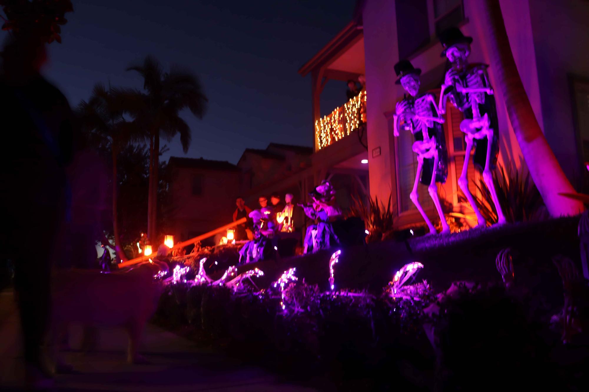 Trick-or-treaters stand in awe before a married skeleton couple and small ghosts. This house was one of many on the street that take pride in their vibrant Halloween decorations.