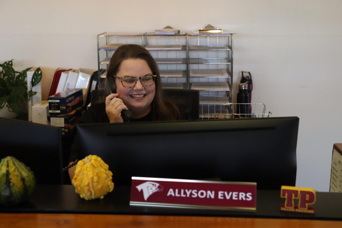 Receptionist Allyson Evers answers the phone with a smile. Evers worked in the hospitality industry for over 10 years before pivoting in the direction of education. 