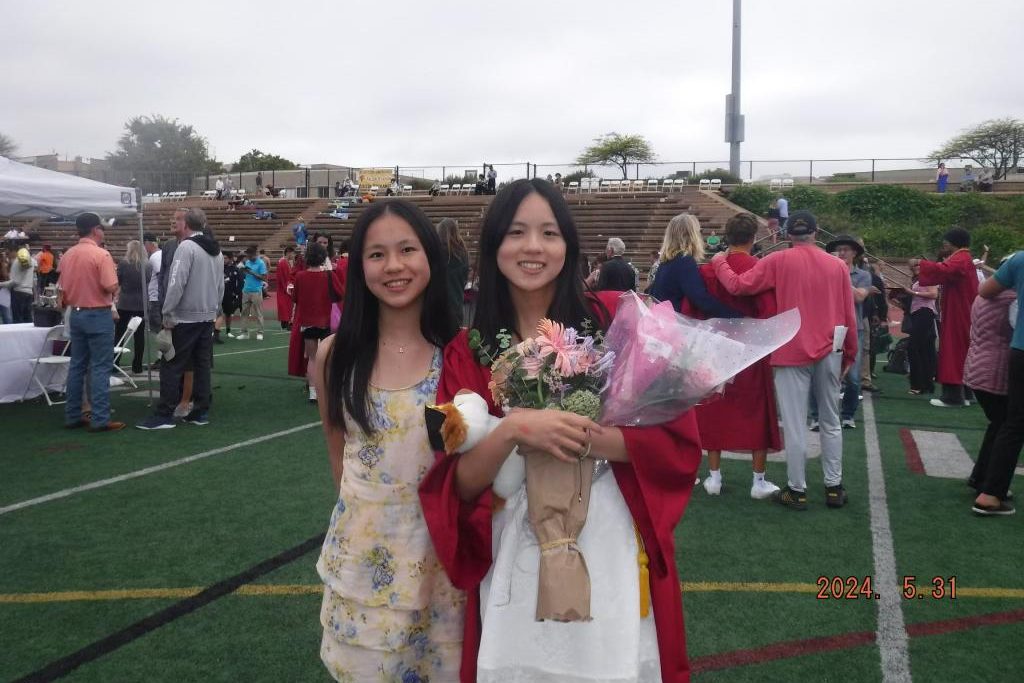 Ayla Tang (11) and Somie Tang ('24) pose on Ed Burke Field after the graduation ceremony. Somie began her schooling at the University of British Columbia this school year. Photo courtesy of Ayla Tang.