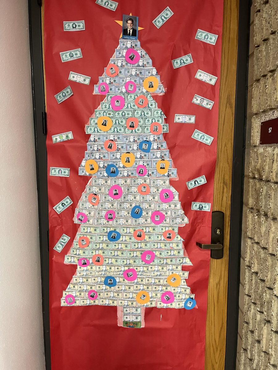 AP Macroeconomics and AP World History teacher Jeffrey Owen's classroom door displays a tree made from dollar bills. The tree is ornamented with photos of students from his first period class.