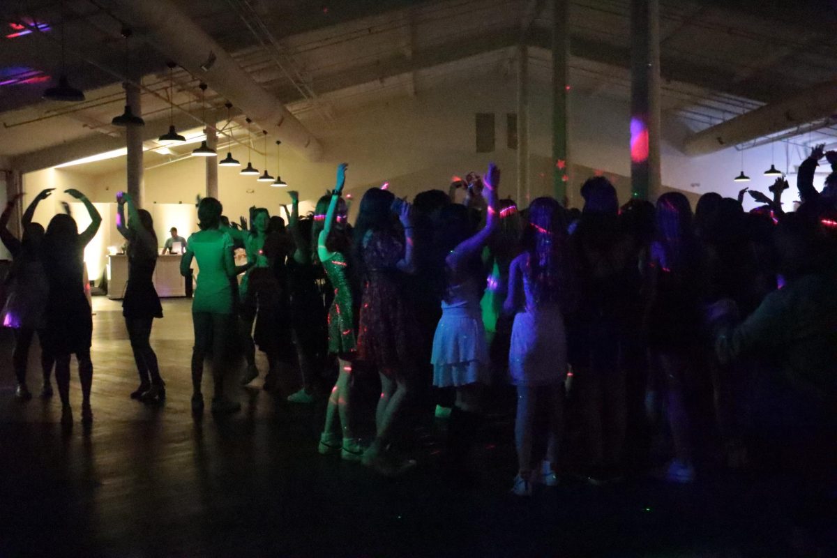 Students dance to 'HOT TO GO!' by Chappell Roan. Under colorful lights, the dance floor was full of energy.