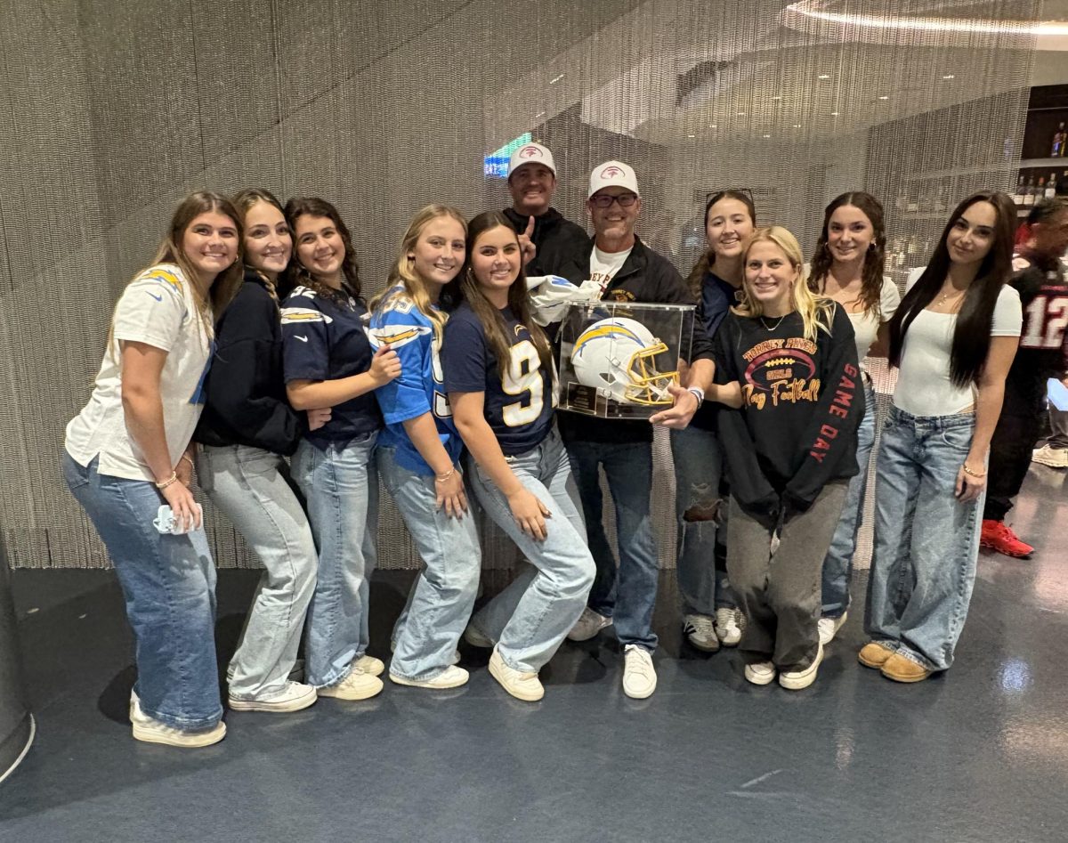 From left to right: Catherine Tonelli (12), Lauren Mills (12), Audrey Davidson (12), Lauren Johnson (12), Charlie O'Connell (12), Brett Ward, Ryland Wickman, Kelly Whelihan (12), Harper Kelley (12), Audra Clark (12), Presley Garcia (12).
Flag football players stand with Coach Ryland Wickman. Wickman received the San Diego Flag Football Coach of the Year award from the Los Angeles Chargers. Photo courtesy of Ryland Wickman.