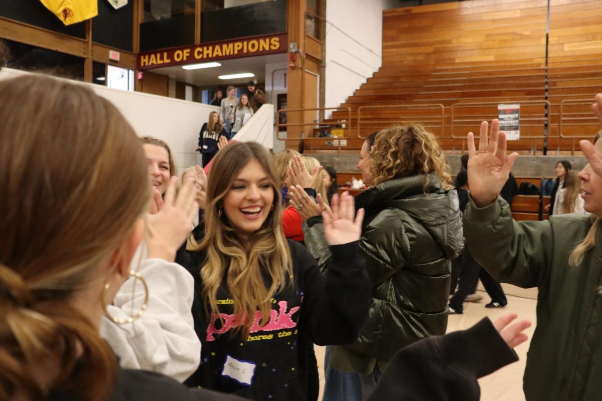 Students smile and high-five as they enter Challenge Day. Challenge Day has been held in around 2,700 schools worldwide, with over one million students having participated. Center: Alexa Quinones (10).