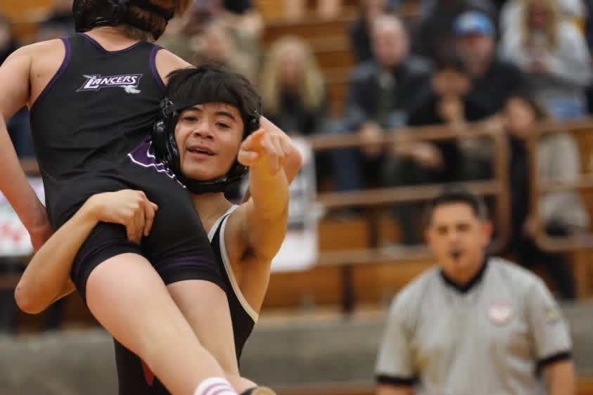 March male Athlete of the Month Jacob Cava (12) points at the camera as he lifts his opponent in the air. Cava has been apart of the wrestling program at the school since freshman year. Photo courtesy of Jacob Cava. 