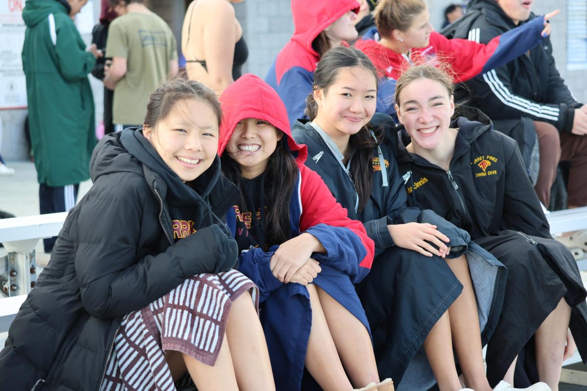 Left to right: Anita Qian (10), Grace Xu (10), Isabel Do (10) and Jade MacInnis (9) smile for the camera in their parkas while waiting for the meet to begin. They attended the Del Norte High School dual meet on March 13. Photo courtesy of Layne Lozano.