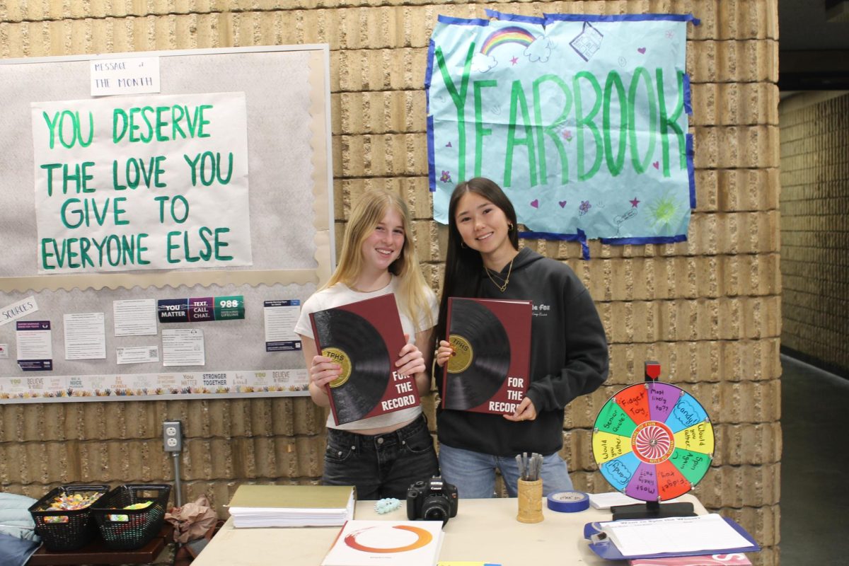 Yearbooks in hand, the Yearbook staff promotes their class. The Freshman Welcome Night included booths from the Career Technical Education Pathway classes. Left to right: Kiki Hoglen (11) and Samantha Huyghe (11).