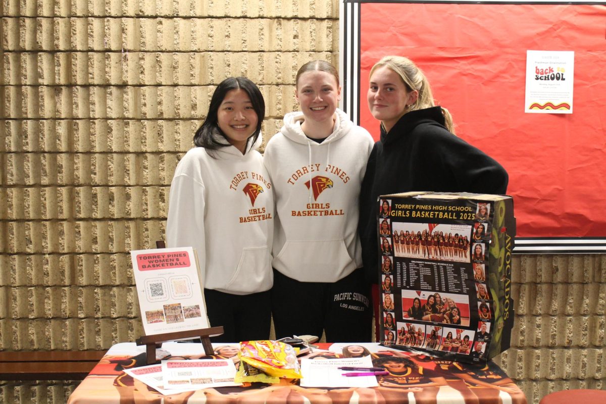 The girls basketball team huddle together for the picture. Candies, sign-up sheets and pictures dress up the booth. Left to right: Averi Kwok (12), Charley Pegg (11) and Addie Knauf (11).