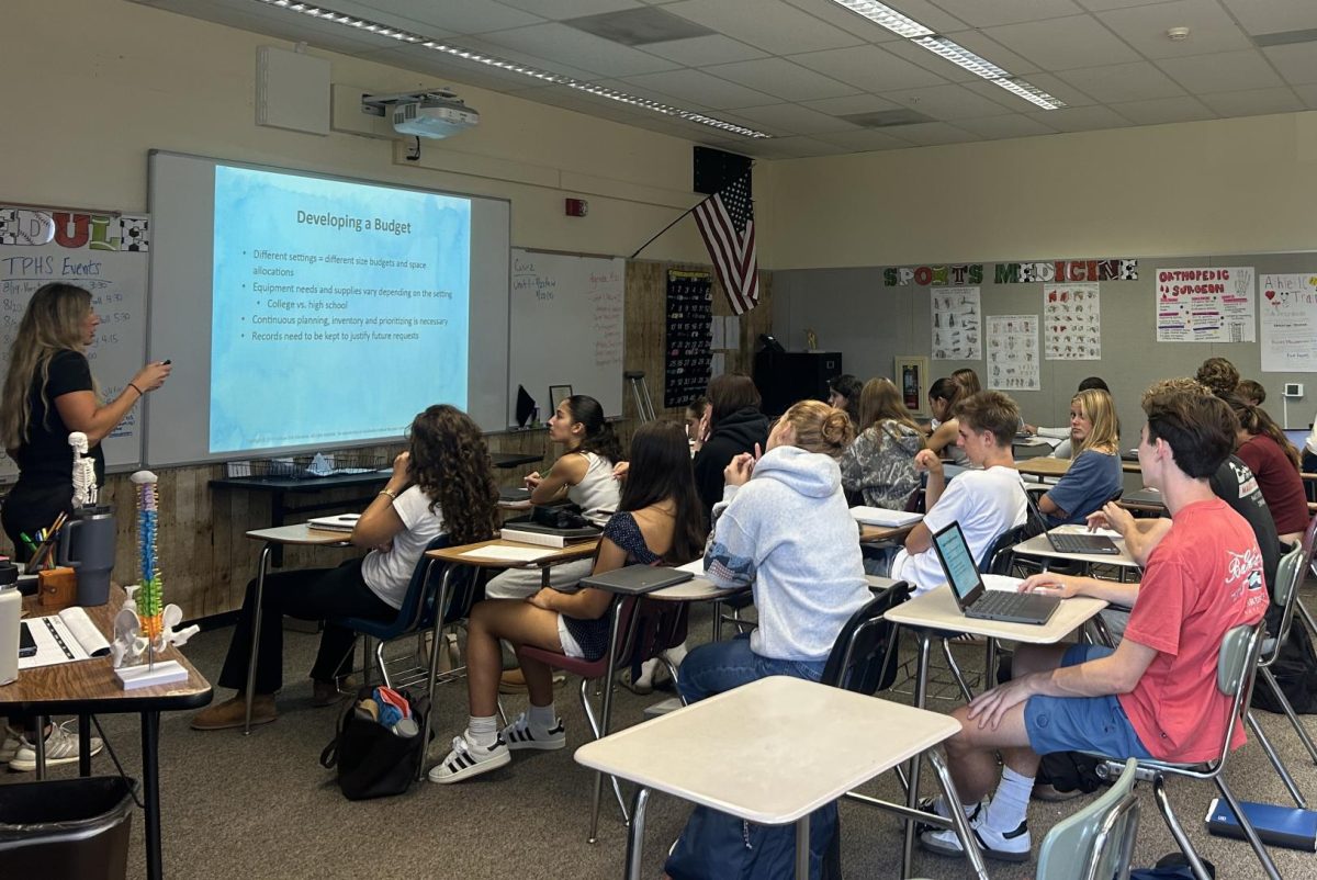 Lacey Sovacool lectures her fourth period Sports Medicine class, describing the process of developing budgets based on different settings and needs for equipment. Sports Medicine, which became a Career Technical Education pathway this year, was previously an external program at the school.