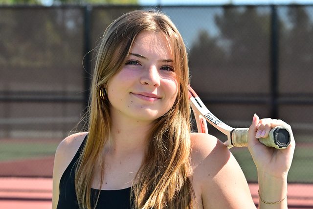 Ruby Resch (11) smiles for a picture to commemorate the start of the girls varsity tennis season. Resch joined the varsity team her freshmen year. Photo courtesy of Anna Scipione. 