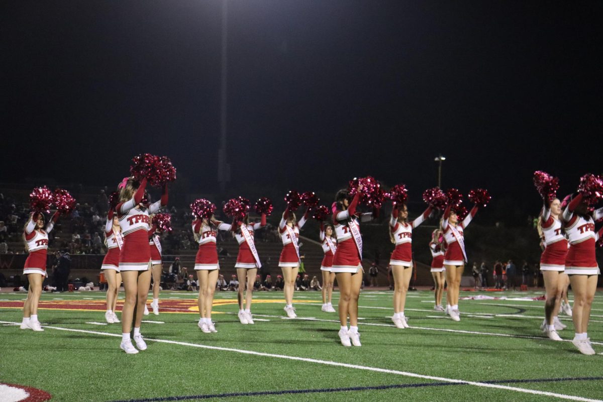 Varsity cheer team dance their choreographed moves to up-beat music. Prior to the game, the senior cheerleaders were honored by walking with their parents and other family members, with their name banners strapped across their bodies and flowers in hand.