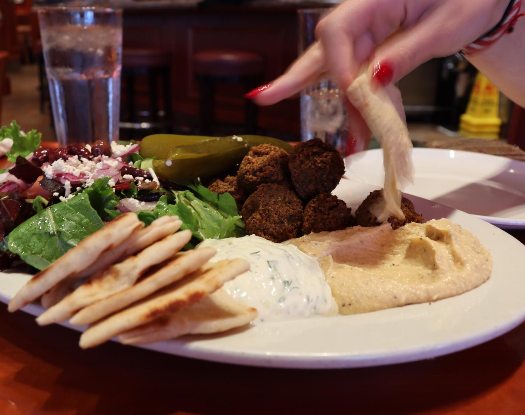 Mari Kradjian dips pita in hummus. The platter also featured a tzatziki dip, pita bread, a Middle Eastern pickle and a Mediterranean salad. 