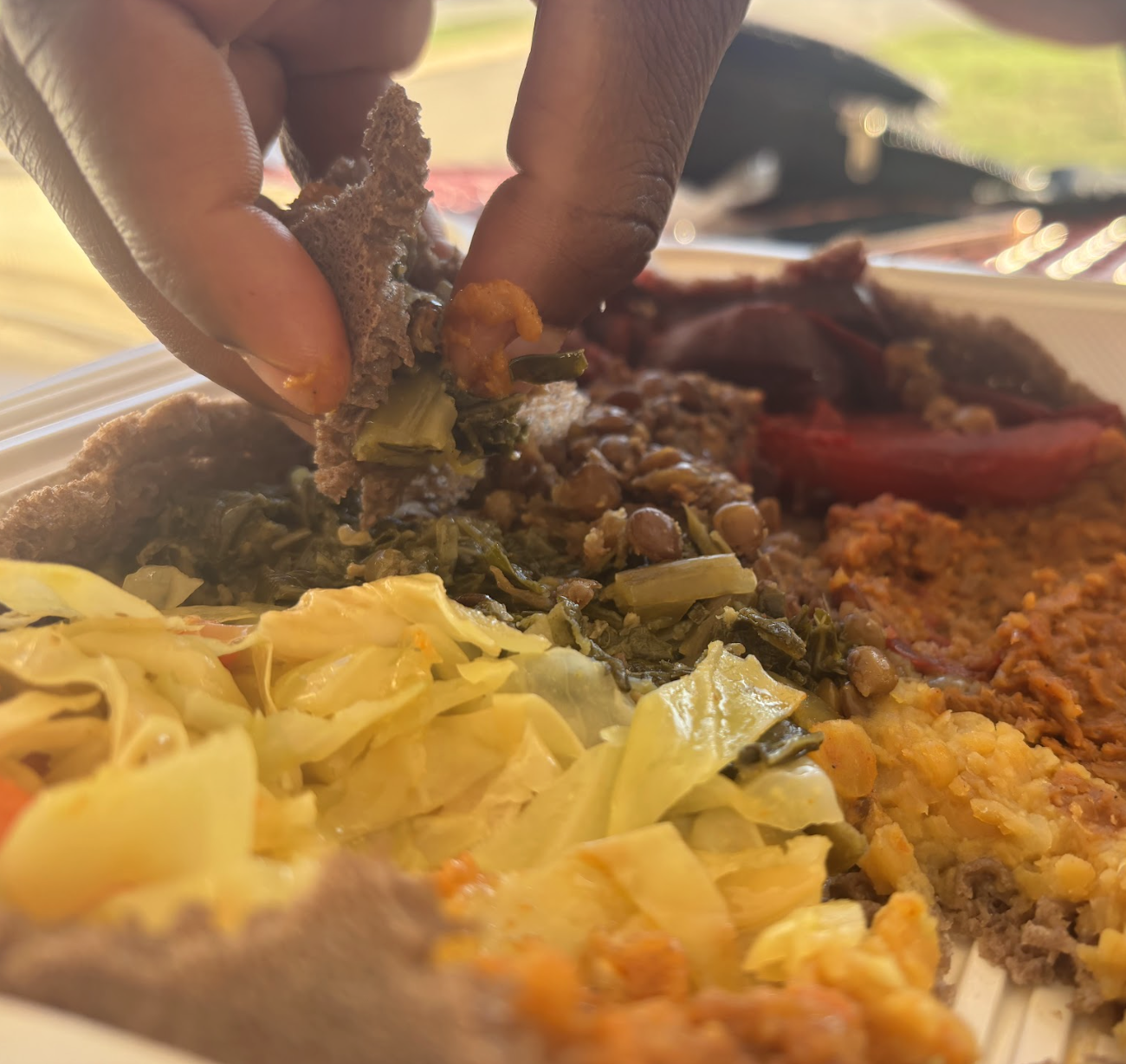 Campus supervisor Martha Whyte uses a piece of injera to scoop up lentils. Meant to be eaten communally, the platter offered a variety of options for each bite.