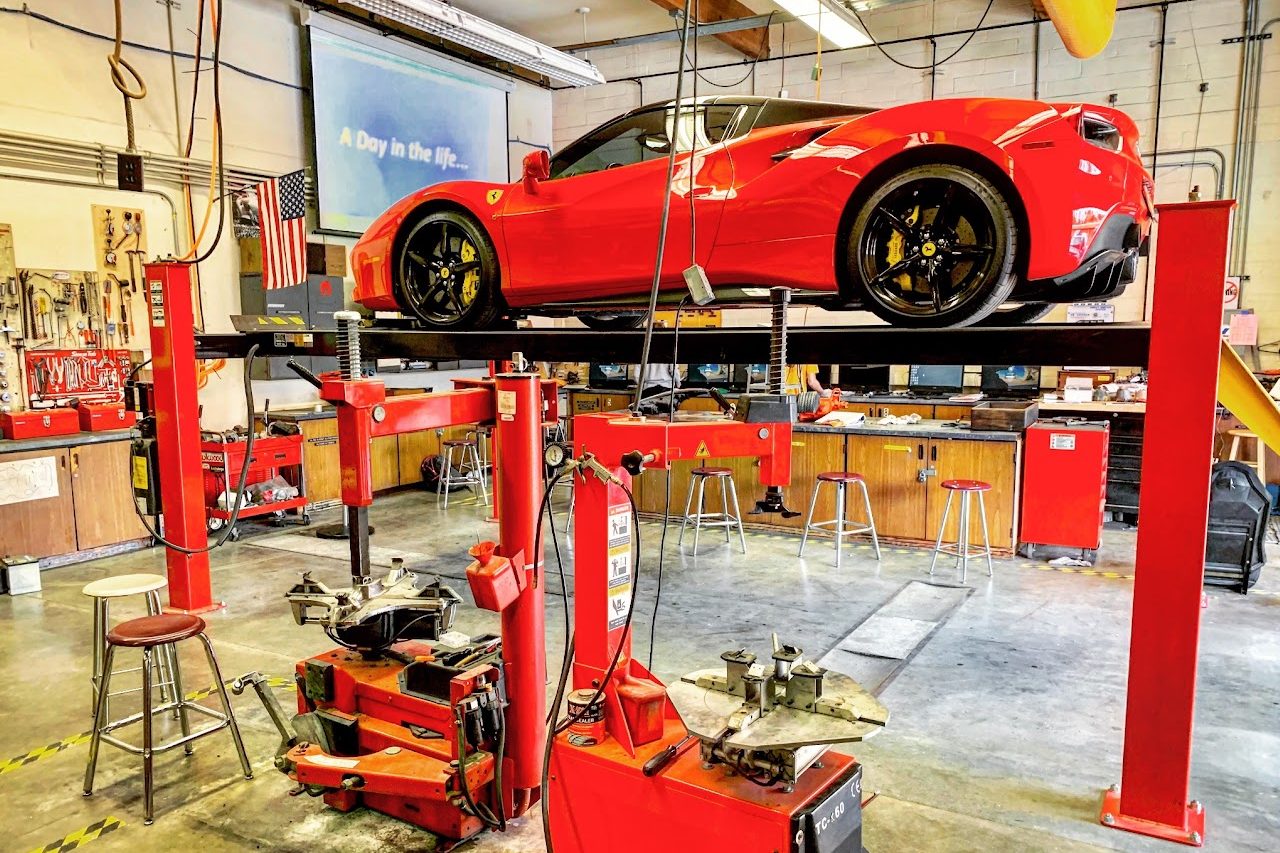 A sports car is raised on a car lift in the auto shop room. Many students brought their own cars to the school's auto shop for repairs and maintenance. Courtesy of Eric Neubauer.