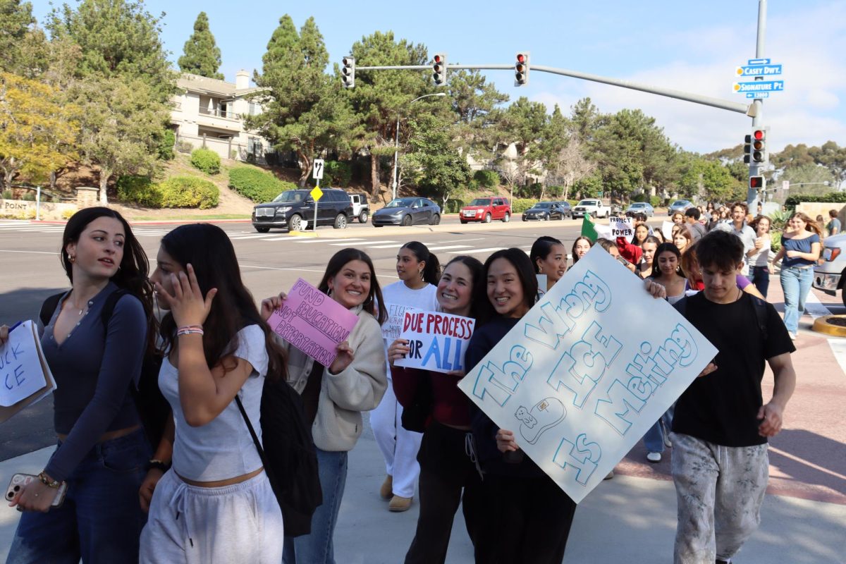 (Left to right) Taylor Faassen (12), Shea Faassen (12) and Emi Kiyota (12) smile with their signs as they cross El Camino Real. They were part of the hundreds of students that walked out.