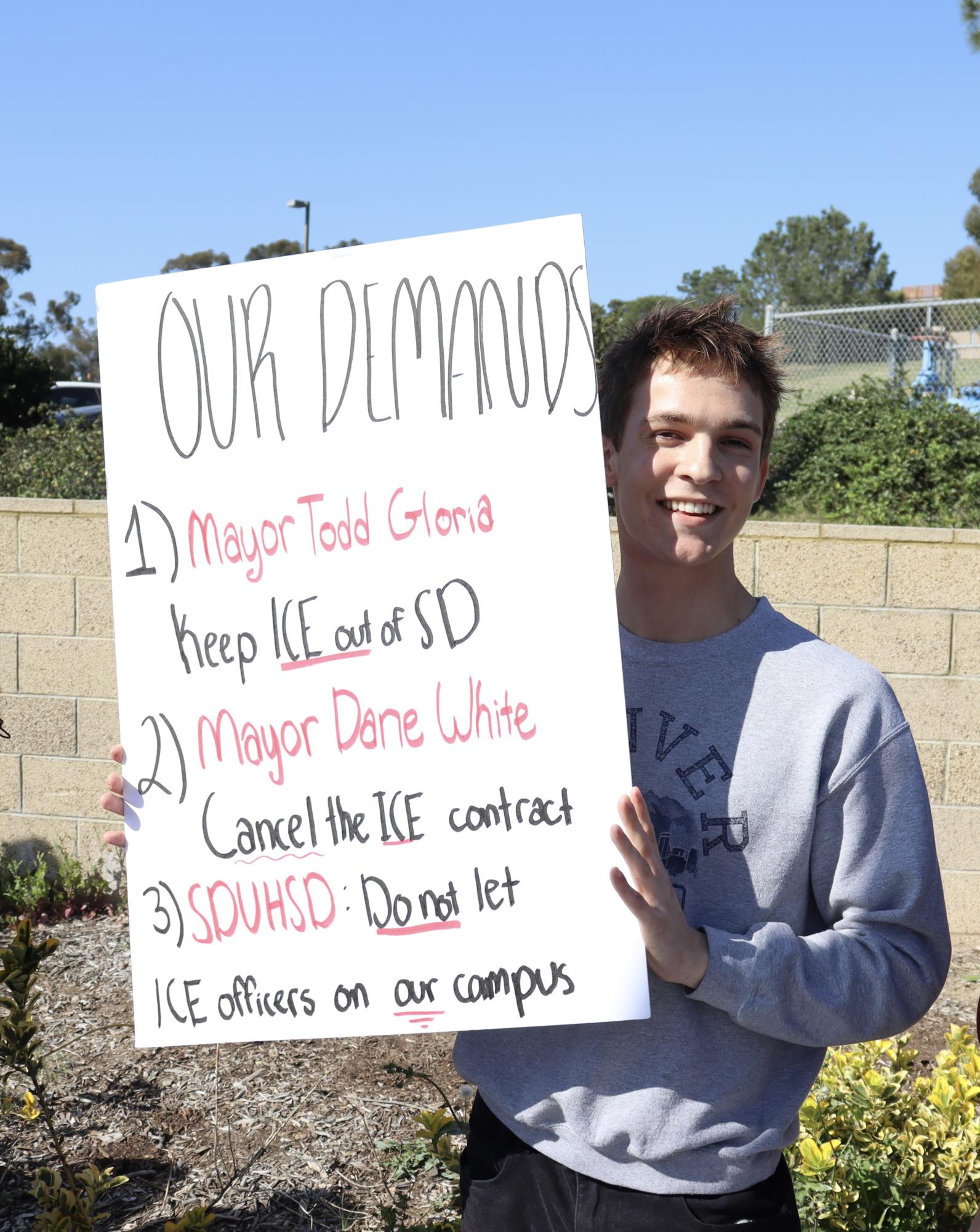 Organizer of the school's walkout Trey Riddle (11) holds up a poster of his three demands. These include calling on Mayor Todd Gloria to remove ICE from the city, Escondido Police Department to cut ties with ICE training and the District to revise SDUHSD Administrative Regulation 5145.13, which currently allows federal agents to enter campus without a judicial warrant.