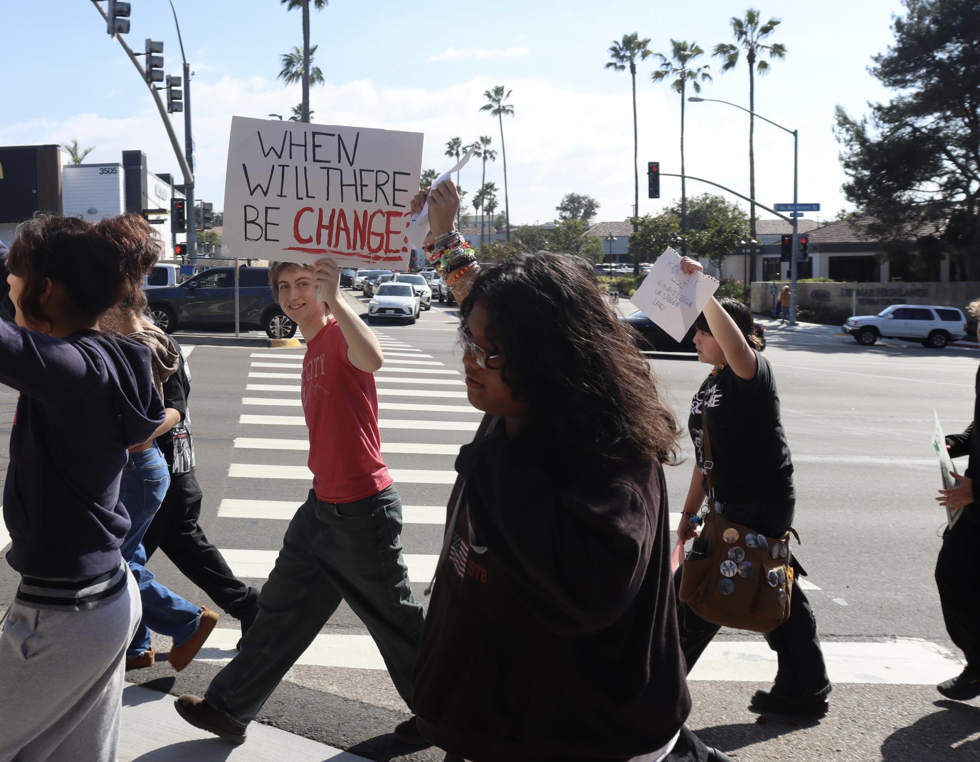 Bronwyn Roberts (11) holds up a sign "When will there be change?" Like Roberts, other participants at the school's walkout created signs in protest of ICE.