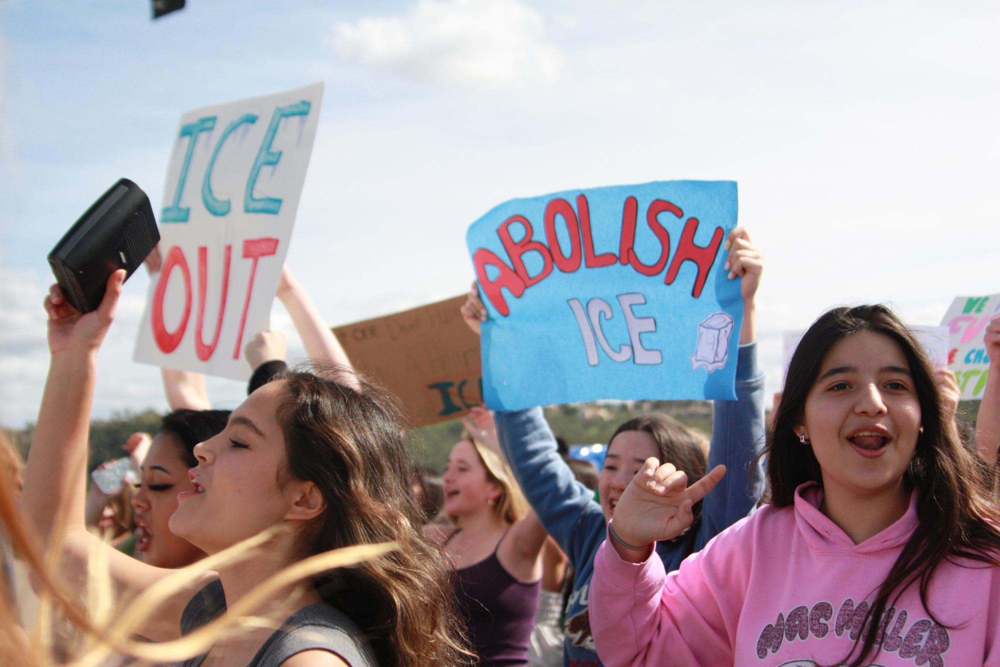 A blue colorful poster reads "Abolish ICE." Students chanted in support of protest.
