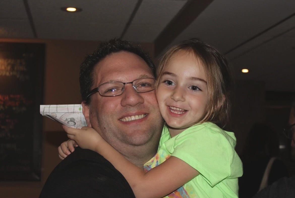Shayna Dolin (10) and her uncle hug in a family photo. This article reflected on the significance of charitable giving and personal growth through the tradition of gelt during Hanukkah.
