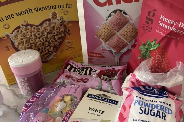 Ingredients and cookie decorations sit on a counter, including cereal, white chocolate, powdered sugar, candies and sprinkles. These items were used to make the snack mix and decorate the Valentine’s sugar cookies.
