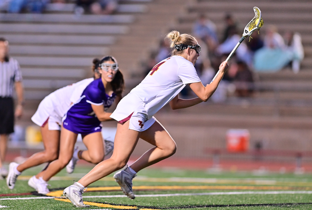 Reese Rohbrach (12) outruns a player on the opposing team while keeping the ball in the pocket of her lacrosse stick. Rohbrach was named female Athlete of the Month for April. Photo courtesy of Anna Scipione. 