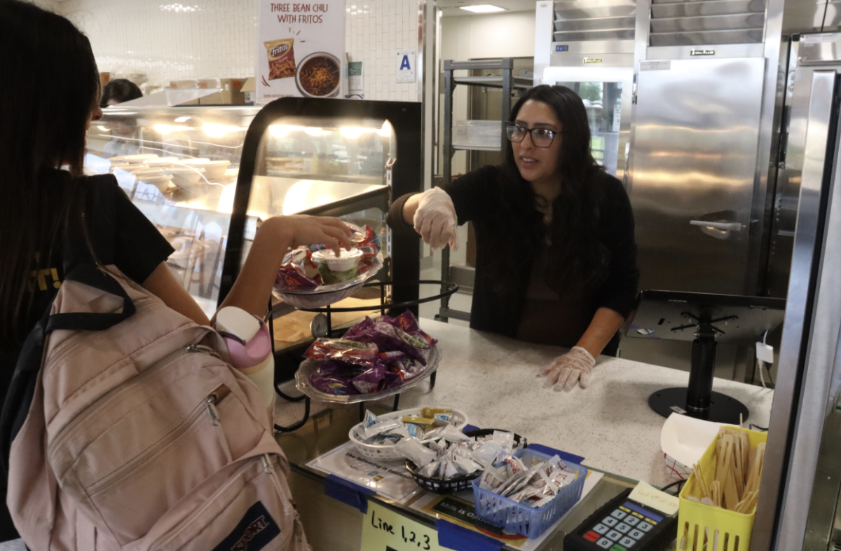 Krystle Harris helps a student select a fruit for lunch. Harris is currently pursuing a degree in nutrition.