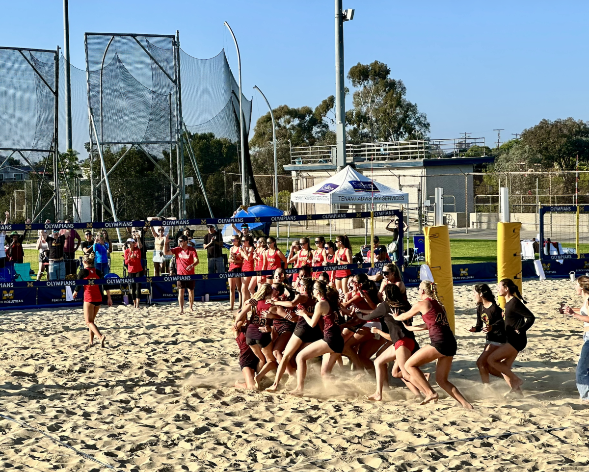 The girls beach volleyball team celebrates Conner Oxberry (11) and Lilia Decker (11) final point in the third set. The team beat the Cathedral Catholic Dons after losing to them three years in a row. Photo courtesy of Sam Krystkowiak.