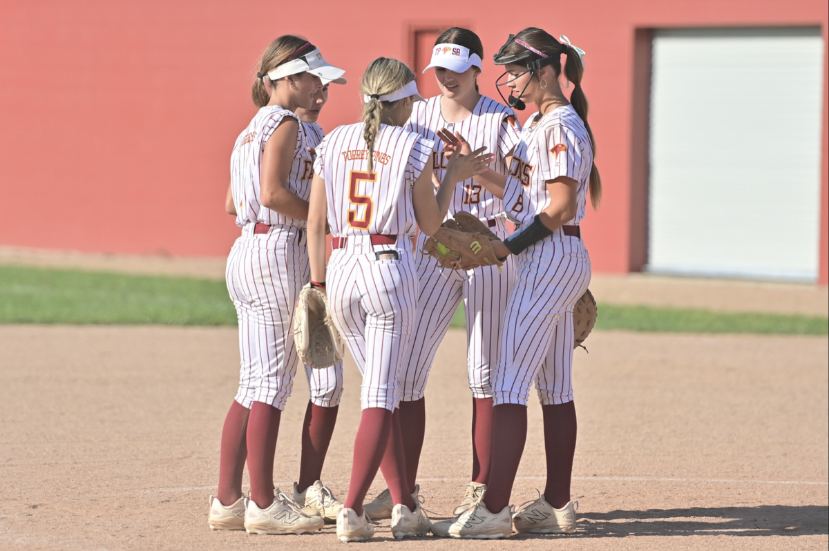 (Far right) Reagan Cullivan (12) and her varsity softball teammates convene at game against Cathedral Catholic High School last Wednesday. She was named Female Athlete of the Month. Photo courtesy of Anna Scipione.